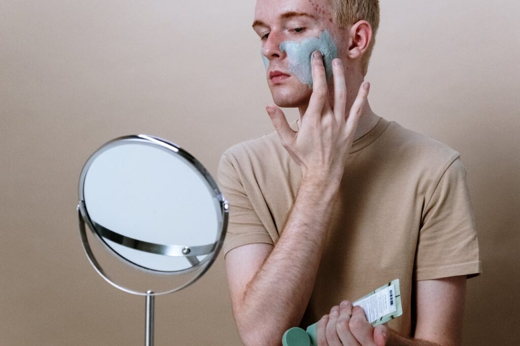 man applying clay mask as part of face treatment routine for men